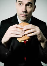 Man eating hamburger with tomato sauce dripping