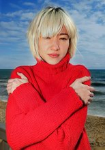 A girl relaxing by the sea on a winter day wearing a warm sweater